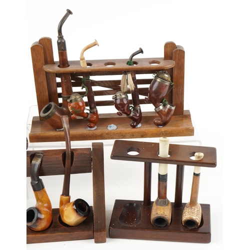 1296 - Twenty one vintage tobacco smoking pipes arranged in six pipe racks, two in the form of a gate, the ... 