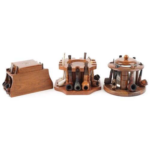 1321 - Twenty four vintage tobacco smoking pipes arranged in three pipe racks with tobacco boxes, some clay... 