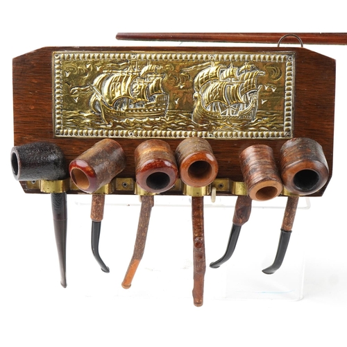 1275 - Twenty vintage tobacco smoking pipes arranged in three pipe racks, two wall hanging, some cherry woo... 