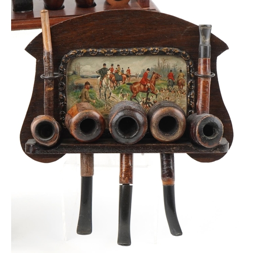 1275 - Twenty vintage tobacco smoking pipes arranged in three pipe racks, two wall hanging, some cherry woo... 