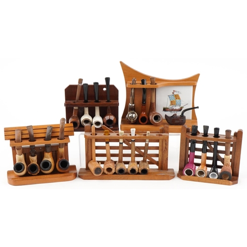 1263 - Twenty three vintage tobacco smoking pipes arranged in five pipe racks, two in the form of a gate, t... 