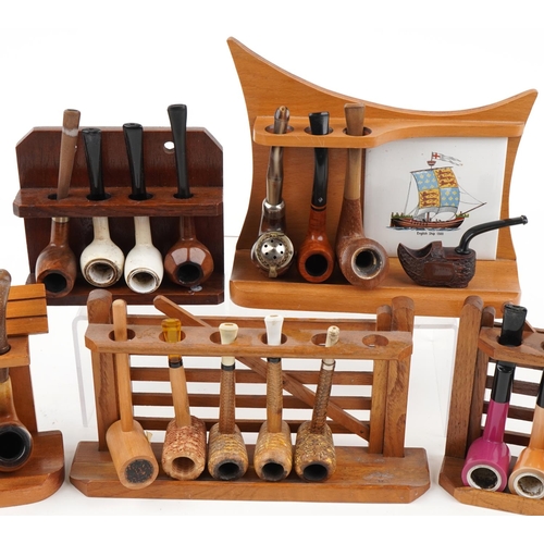 1263 - Twenty three vintage tobacco smoking pipes arranged in five pipe racks, two in the form of a gate, t... 