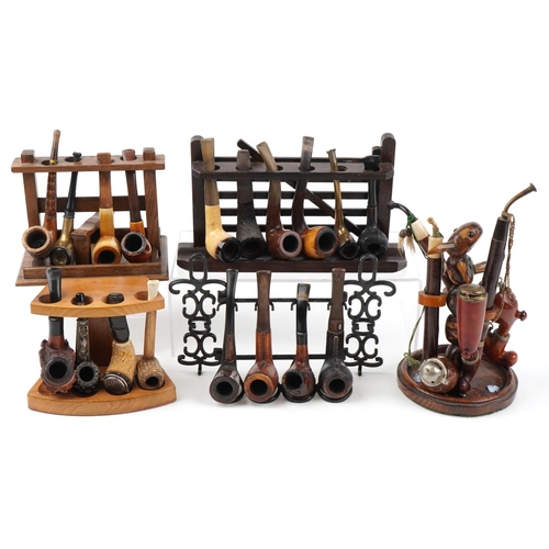 1264 - Twenty one vintage tobacco smoking pipes, some European, arranged in five pipe racks, one carved wit... 