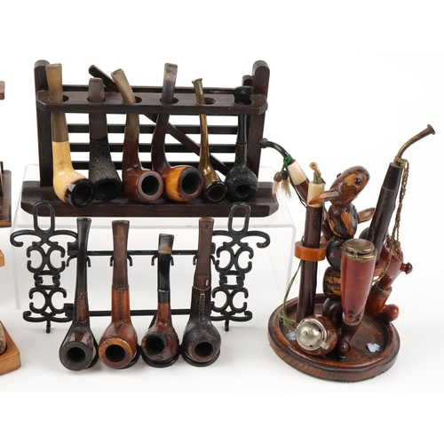 1264 - Twenty one vintage tobacco smoking pipes, some European, arranged in five pipe racks, one carved wit... 