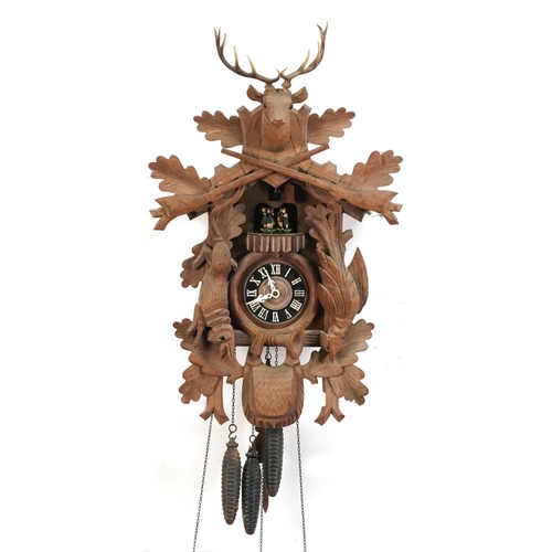 695 - German Black Forest cuckoo clock carved with a deer's head and game having a circular dial with Roma... 