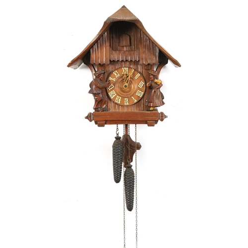 696 - German Black Forest cuckoo clock carved with two figures having circular dial with Arabic numerals, ... 