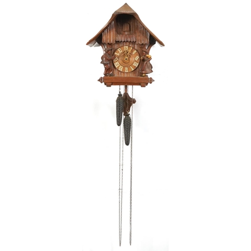 696 - German Black Forest cuckoo clock carved with two figures having circular dial with Arabic numerals, ... 