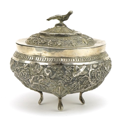 75 - Chinese export unmarked silver four footed bowl and cover profusely embossed with birds amongst cher... 