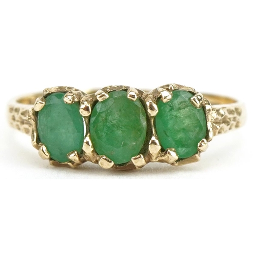 3185 - 9ct gold emerald three stone ring with engraved shoulders, size N, 2.1g