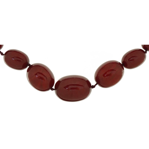 3046 - Large cherry amber graduated bead necklace, the largest bead approximately 35mm x 26mm in diameter, ... 