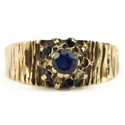 3507 - 9ct gold sapphire and clear stone flower head ring with naturalistic shoulders, size N/O, 3.0g