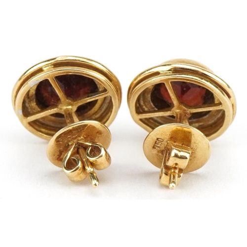 3139 - Pair of two tone gold garnet solitaire stud earrings, the backs marked 750, 13mm in diameter, 7.7g