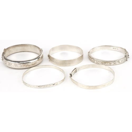 3422 - Five silver bangles four engraved with foliage, total 78.5g