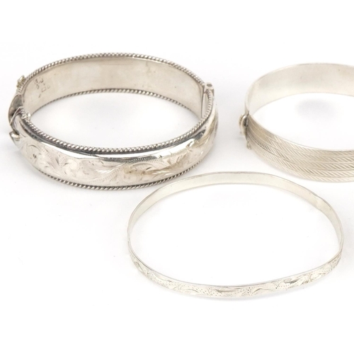 3422 - Five silver bangles four engraved with foliage, total 78.5g