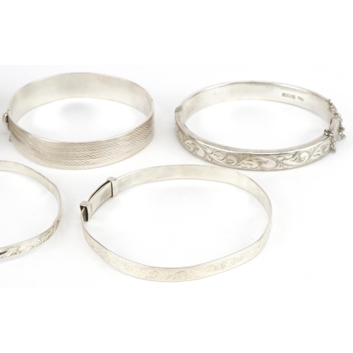 3422 - Five silver bangles four engraved with foliage, total 78.5g