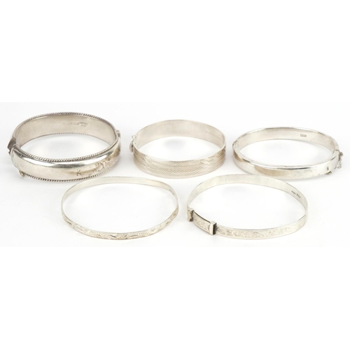 3422 - Five silver bangles four engraved with foliage, total 78.5g