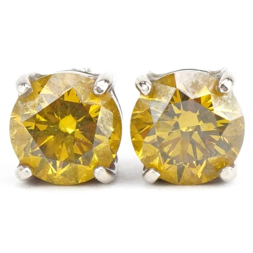 3174 - Pair of white metal yellow diamond solitaire stud earrings with certificate, total diamond weight ap... 