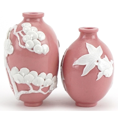 61 - Two Chinese porcelain pink ground snuff bottles decorated in relief with fish and a crane, the large... 