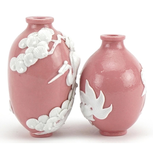 61 - Two Chinese porcelain pink ground snuff bottles decorated in relief with fish and a crane, the large... 