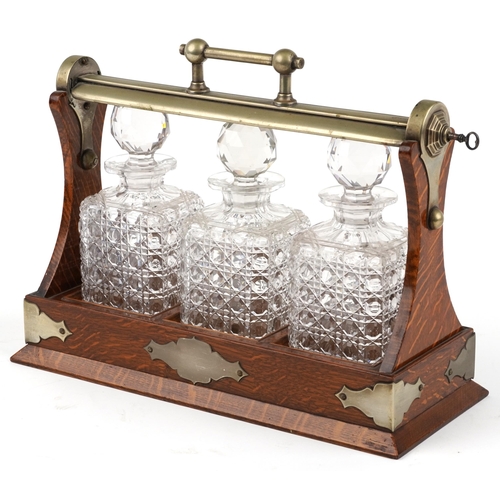 228 - Edwardian oak Grimsell's Patent tantalus housing three cut glass decanters, 40cm wide