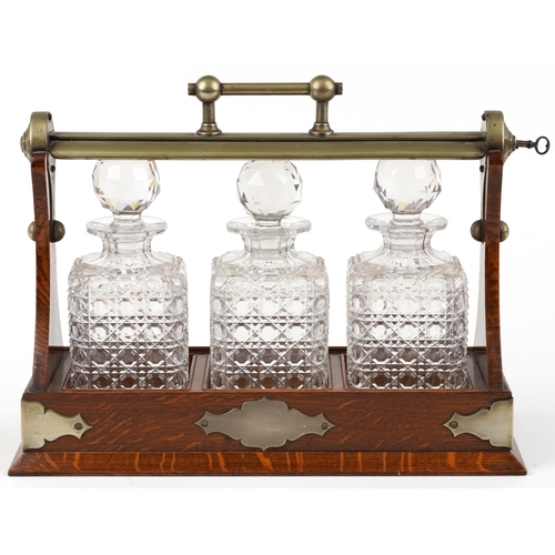 228 - Edwardian oak Grimsell's Patent tantalus housing three cut glass decanters, 40cm wide