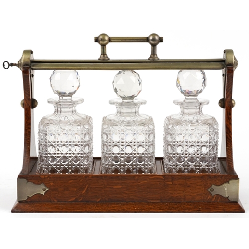 228 - Edwardian oak Grimsell's Patent tantalus housing three cut glass decanters, 40cm wide