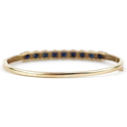 2109 - 9ct gold graduated sapphire and diamond hinged bangle, the largest sapphire approximately 5.20mm x 4... 