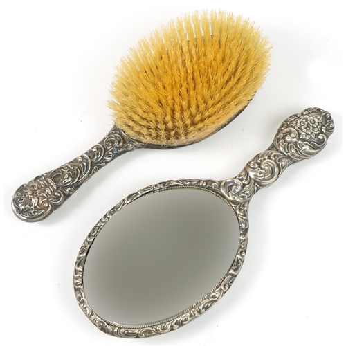 1162 - Victorian silver backed dressing table hand brush and similar mirror, each profusely embossed with f... 