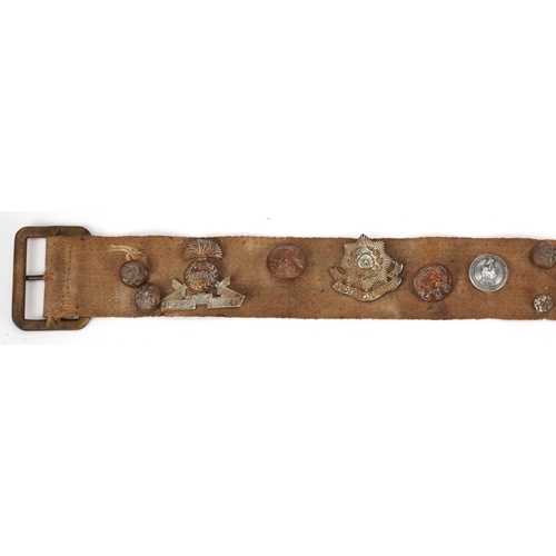 499 - Military interest canvas belt with various cap badges and buttons including East Yorkshire and Lanca... 