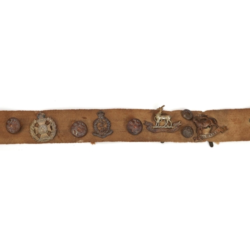 499 - Military interest canvas belt with various cap badges and buttons including East Yorkshire and Lanca... 