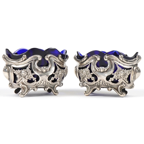 36 - William Oliver, pair of Art Nouveau pierced and embossed silver open salts with blue glass liners, B... 