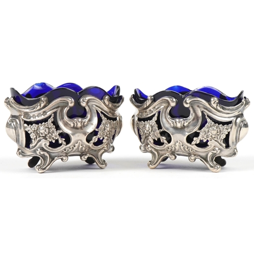 36 - William Oliver, pair of Art Nouveau pierced and embossed silver open salts with blue glass liners, B... 
