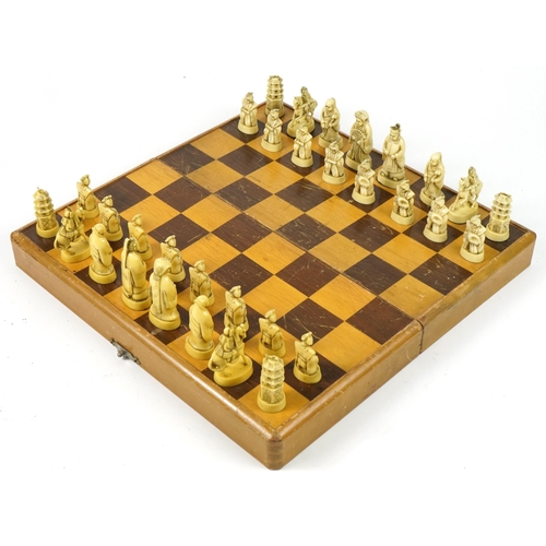 1360 - Chinese ivorine chess set housed in a fitted folding chess board, the chess board 39cm x 40cm