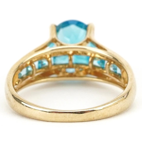 2123 - 9ct gold blue topaz solitaire ring with blue spinel set shoulders, the topaz approximately 10.0mm x ... 