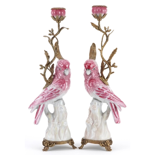 312 - Pair of continental porcelain parakeet design candlesticks with bronze mounts, each 43cm high