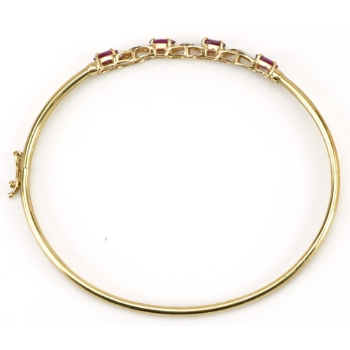 2179 - 9ct gold ruby and diamond crossover hinged bangle, 6.5cm wide, 3.8g