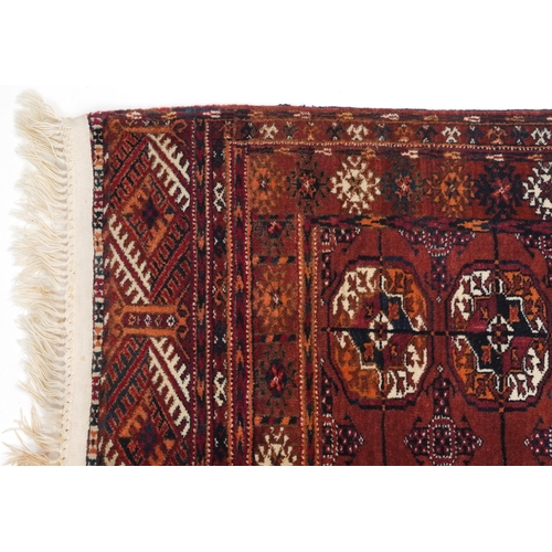 1064 - Rectangular Turkmen red and blue ground rug having an allover geometric design, 118cm x 78cm