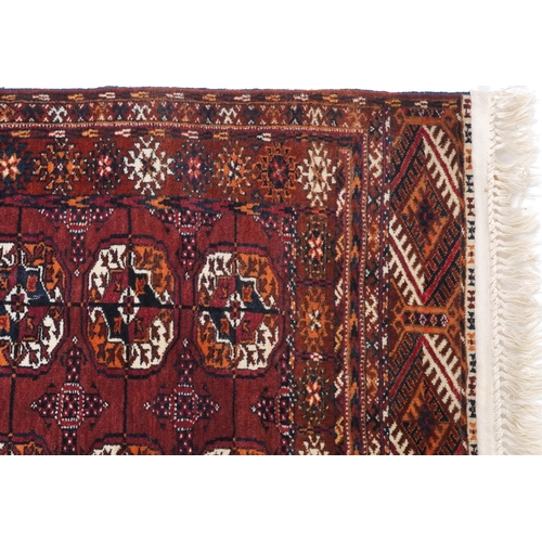 1064 - Rectangular Turkmen red and blue ground rug having an allover geometric design, 118cm x 78cm