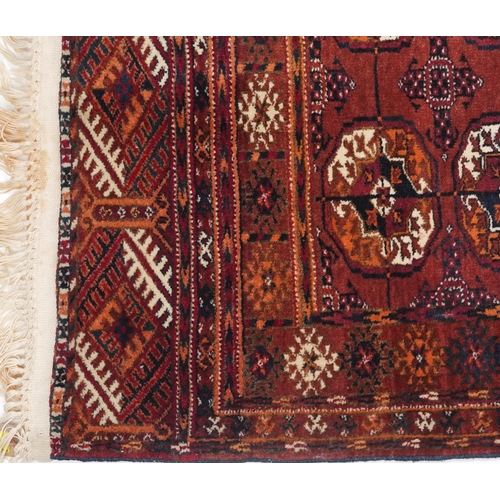 1064 - Rectangular Turkmen red and blue ground rug having an allover geometric design, 118cm x 78cm