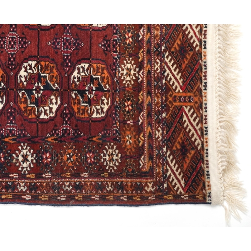 1064 - Rectangular Turkmen red and blue ground rug having an allover geometric design, 118cm x 78cm