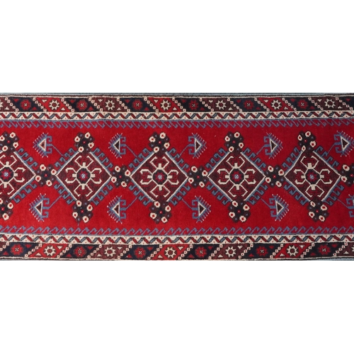 1086 - Turkish Red and blue ground carpet runner having an allover repeat geometric design, 295cm x 75cm