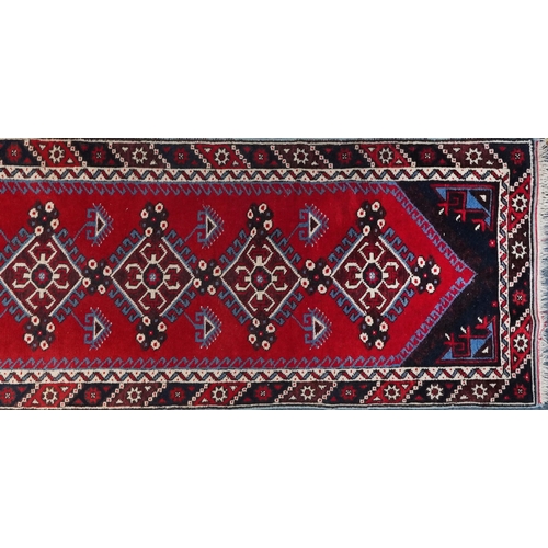 1086 - Turkish Red and blue ground carpet runner having an allover repeat geometric design, 295cm x 75cm