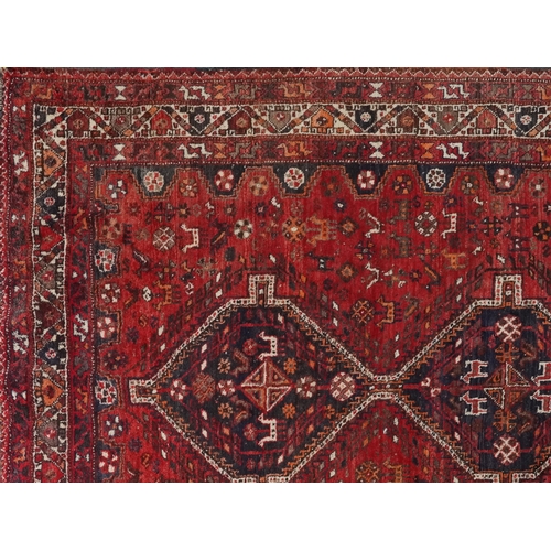 1003 - Persian red and blue ground carpet having an allover geometric and animal design, 295cm x 214cm