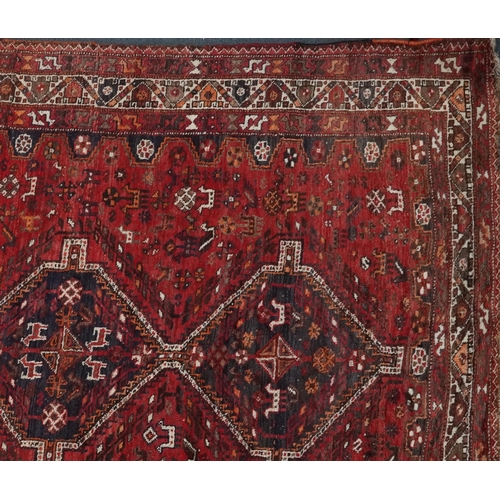 1003 - Persian red and blue ground carpet having an allover geometric and animal design, 295cm x 214cm