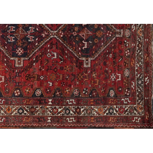 1003 - Persian red and blue ground carpet having an allover geometric and animal design, 295cm x 214cm