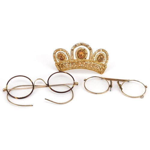 1273 - Two pairs of antique yellow metal spectacles and a yellow metal crown brooch set with orange stones,... 