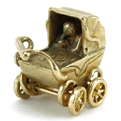 2462 - 9ct gold charm in the form of a baby in a pram with rotating wheels, 1.5cm wide, 3.2g