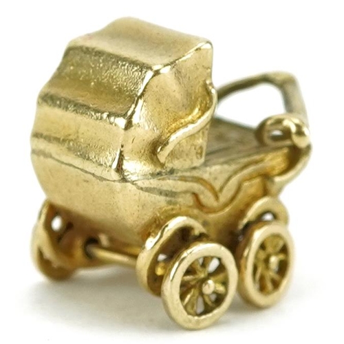 2462 - 9ct gold charm in the form of a baby in a pram with rotating wheels, 1.5cm wide, 3.2g