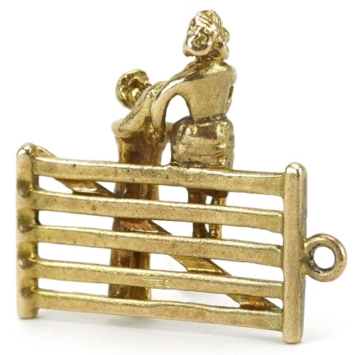 2130 - 9ct gold charm in the form of a gentleman helping a lady down from a gate, 2.1cm high, 4.2g