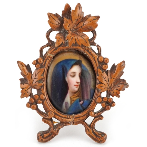 94 - German Black Forest wooden frame carved with leaves and berries housing an oval porcelain plaque han... 